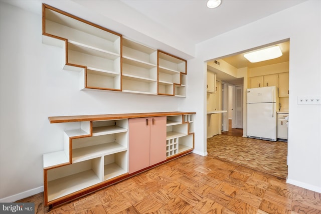 kitchen featuring cream cabinets, light parquet floors, and white fridge