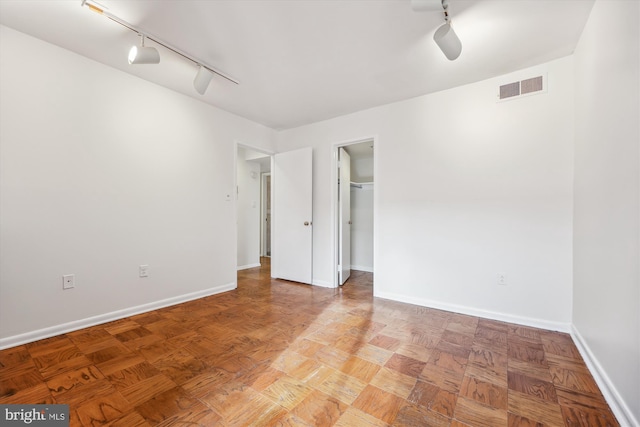 empty room featuring track lighting and light parquet flooring