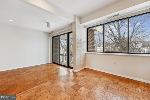 empty room featuring light parquet floors, a healthy amount of sunlight, and beam ceiling