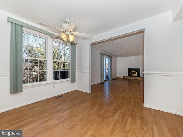 unfurnished dining area featuring hardwood / wood-style floors, a fireplace, and ceiling fan