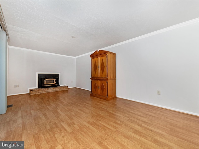 unfurnished living room with ornamental molding, a textured ceiling, a fireplace, and light hardwood / wood-style flooring