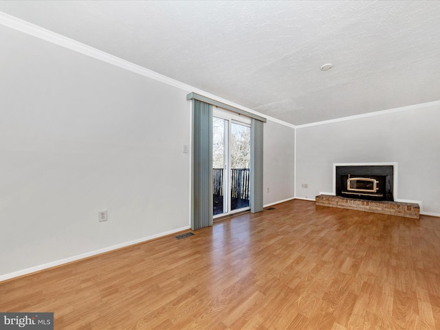 unfurnished living room featuring ornamental molding, a brick fireplace, a textured ceiling, and light wood-type flooring