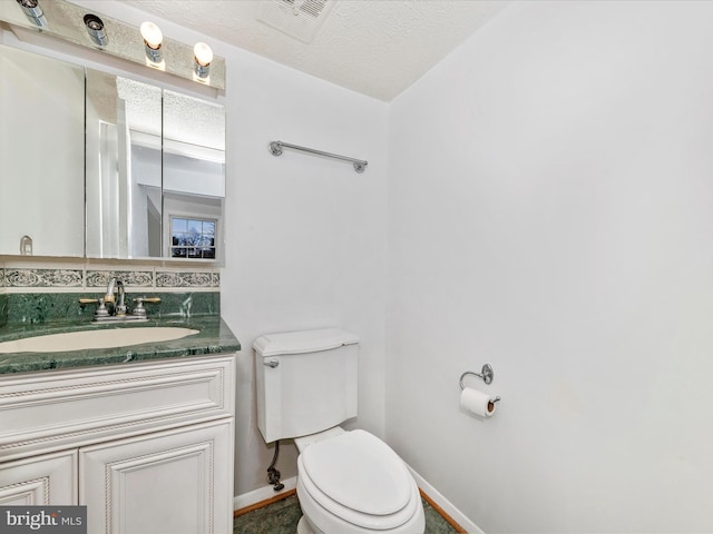 bathroom featuring tasteful backsplash, vanity, toilet, and a textured ceiling