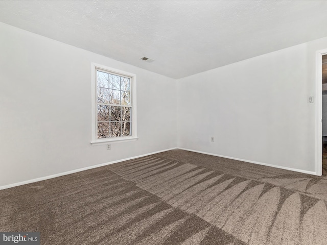 empty room with carpet floors and a textured ceiling