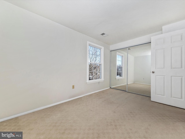 unfurnished bedroom featuring light colored carpet and a closet