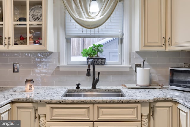 interior details featuring tasteful backsplash, sink, and cream cabinetry