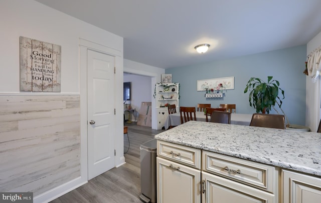 kitchen with light stone counters, light hardwood / wood-style flooring, and cream cabinetry