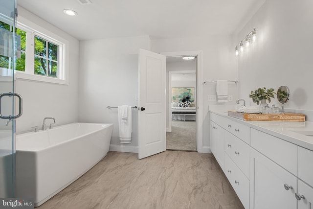 full bathroom with marble finish floor, double vanity, a freestanding bath, a sink, and baseboards