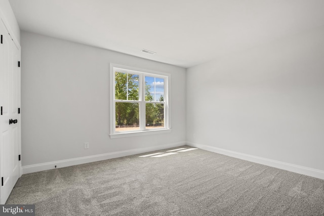 spare room featuring carpet floors, visible vents, and baseboards