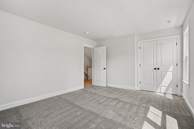 unfurnished bedroom featuring a closet, carpet flooring, visible vents, and baseboards