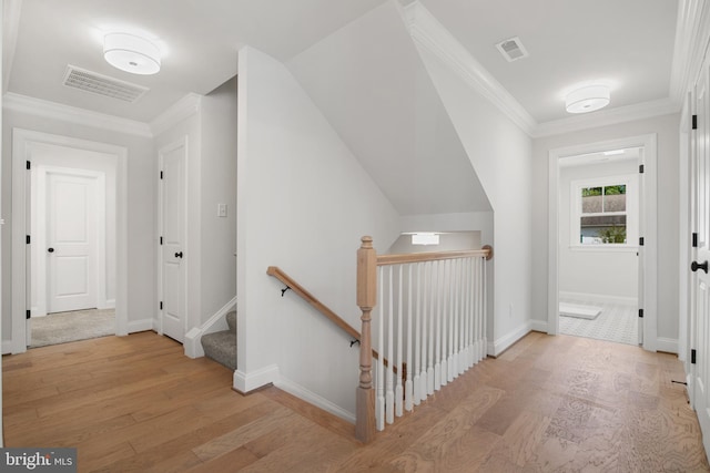 hall featuring ornamental molding, visible vents, an upstairs landing, and wood finished floors