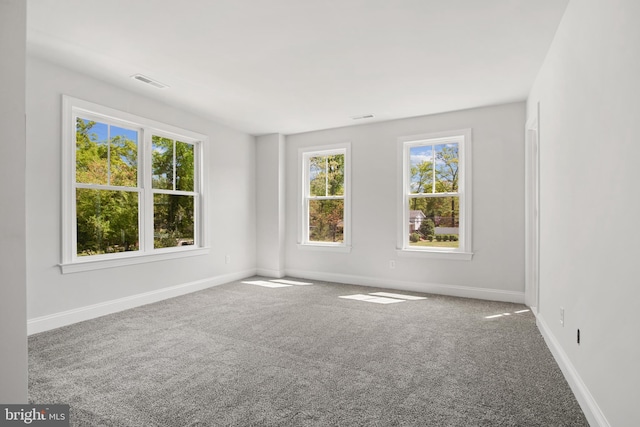 unfurnished room featuring carpet, visible vents, and baseboards