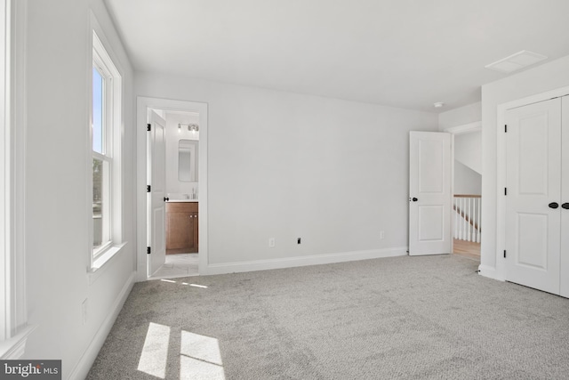 unfurnished bedroom featuring carpet floors, baseboards, and connected bathroom