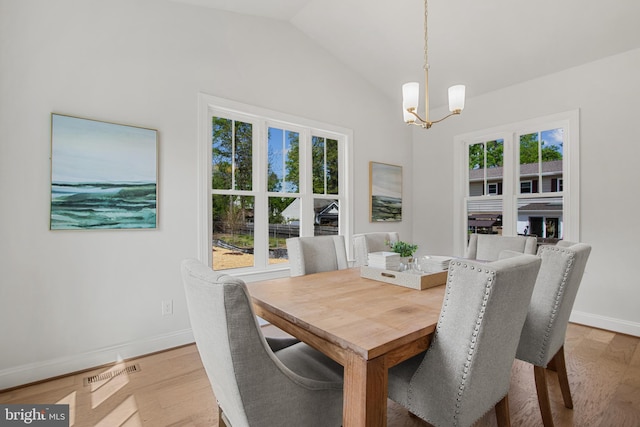 dining space with vaulted ceiling, light wood-type flooring, baseboards, and an inviting chandelier