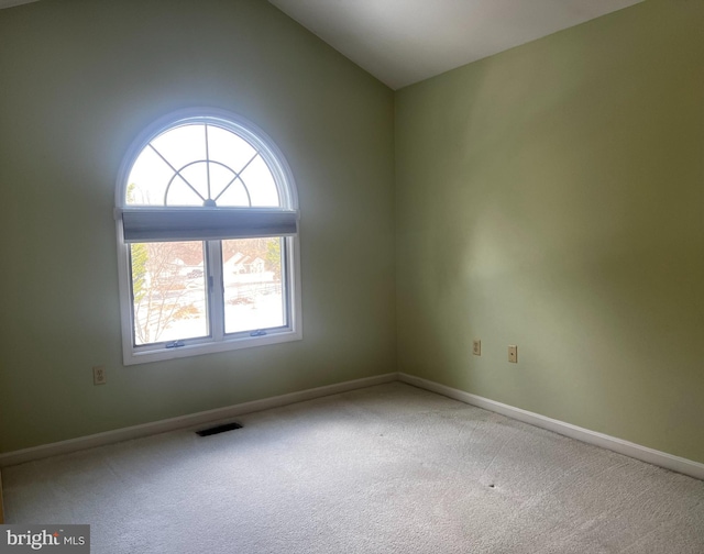 carpeted empty room featuring lofted ceiling