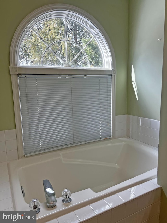 bathroom with a relaxing tiled tub and plenty of natural light