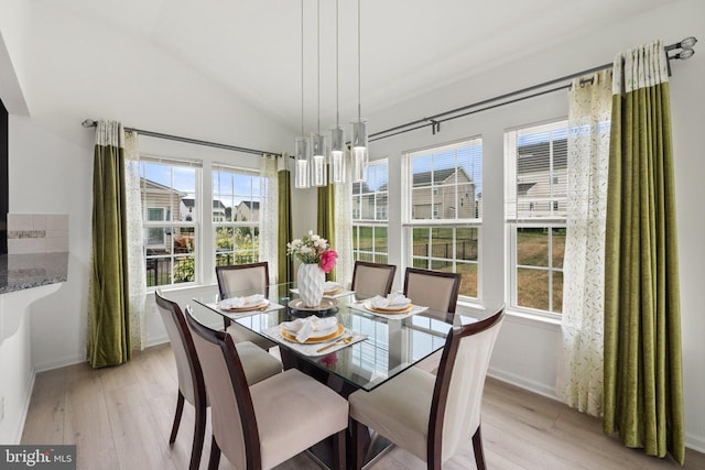 dining space with vaulted ceiling and light wood-type flooring