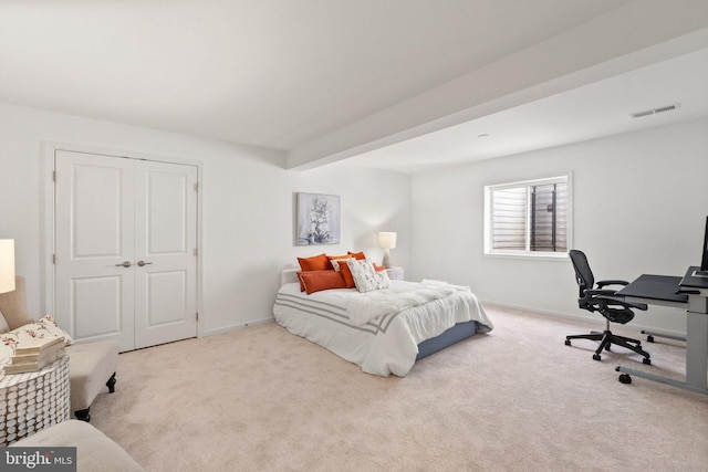 bedroom featuring light carpet, a closet, and beamed ceiling