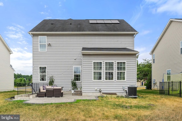 back of property featuring solar panels, central air condition unit, a lawn, an outdoor hangout area, and a patio