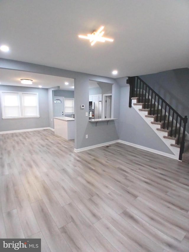 unfurnished living room featuring stairs, recessed lighting, wood finished floors, and baseboards