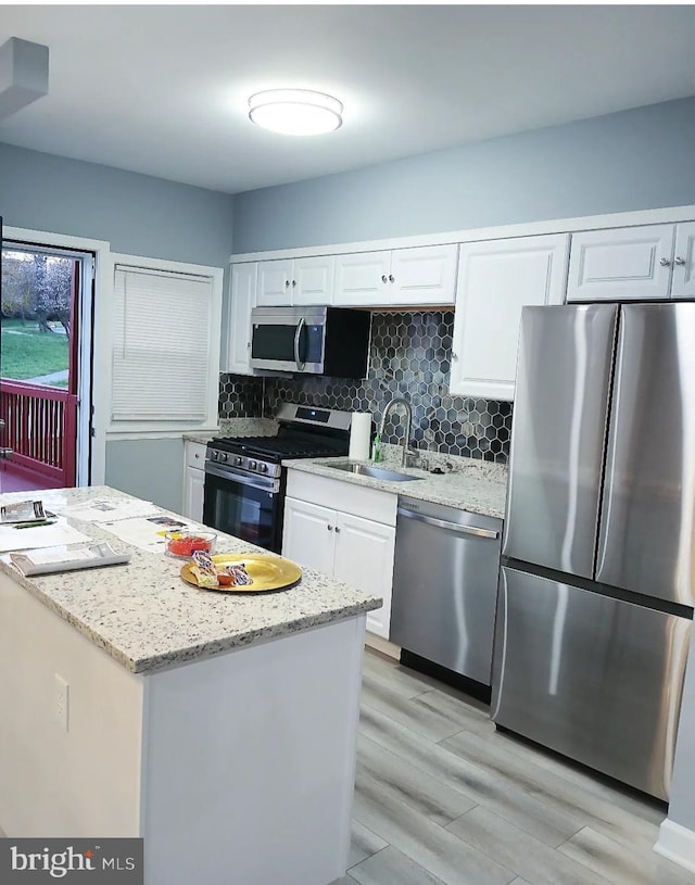 kitchen featuring tasteful backsplash, sink, white cabinets, stainless steel appliances, and light stone countertops