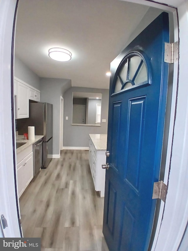 kitchen featuring dishwasher, baseboards, light wood-style flooring, and white cabinets