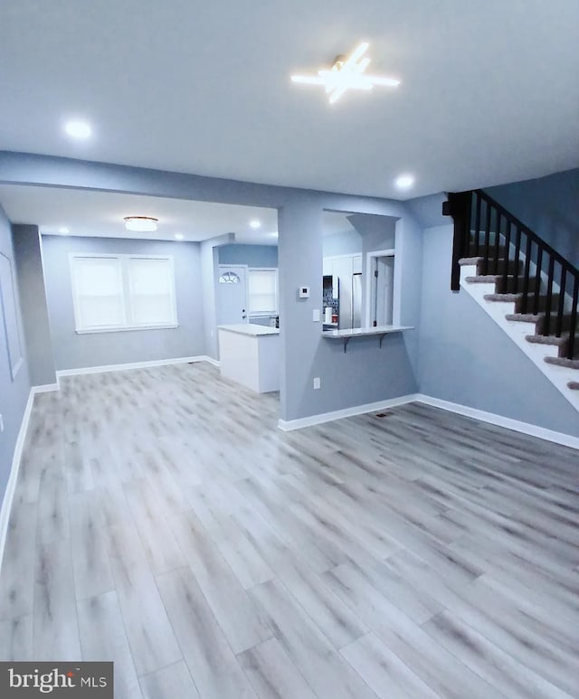 unfurnished living room with recessed lighting, wood finished floors, baseboards, and stairs