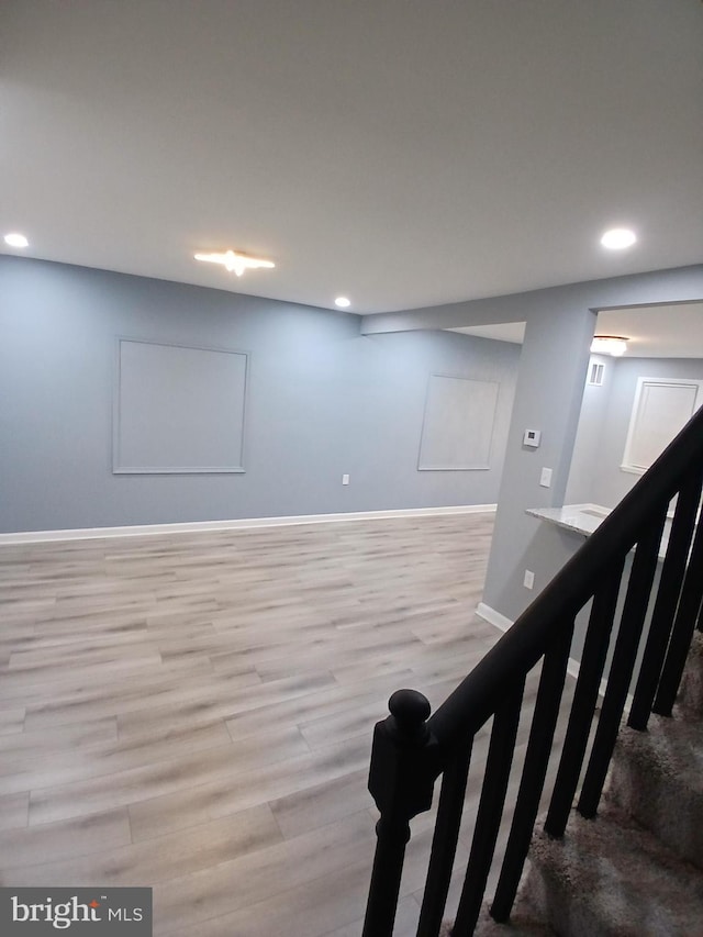 finished basement with recessed lighting, stairway, baseboards, and wood finished floors