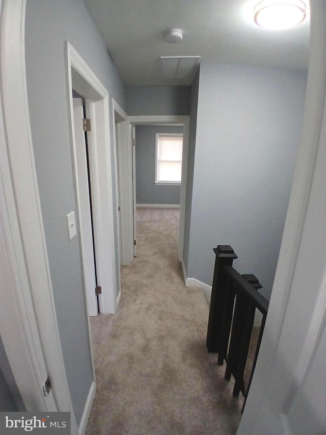 hall with carpet floors, an upstairs landing, and baseboards