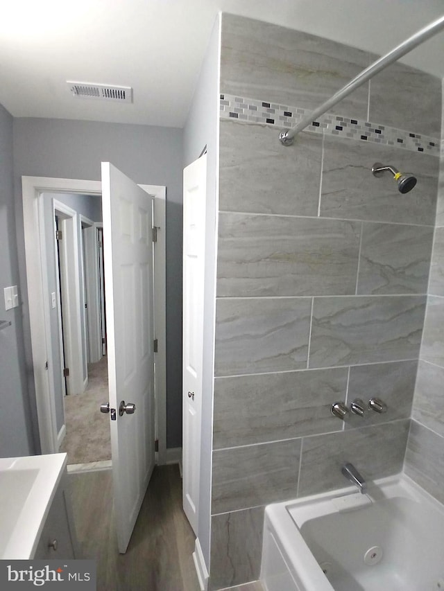 bathroom with vanity, tiled shower / bath combo, and wood-type flooring