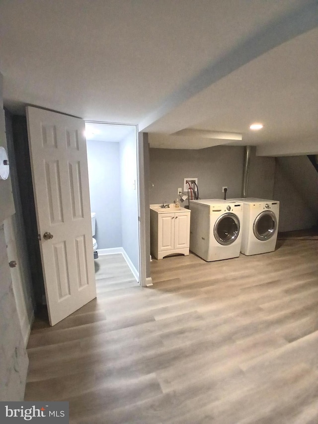 laundry area featuring cabinets, washing machine and dryer, sink, and light hardwood / wood-style floors