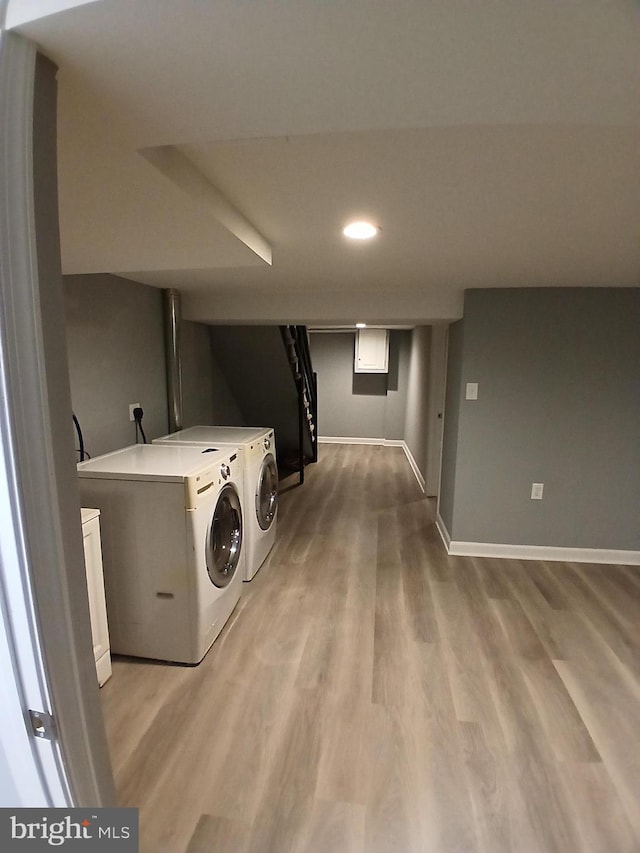 clothes washing area featuring independent washer and dryer, wood finished floors, and baseboards