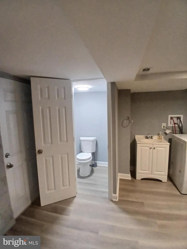 bathroom with toilet, baseboards, visible vents, and wood finished floors