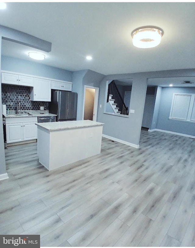 kitchen featuring sink, stainless steel appliances, a center island, tasteful backsplash, and white cabinets