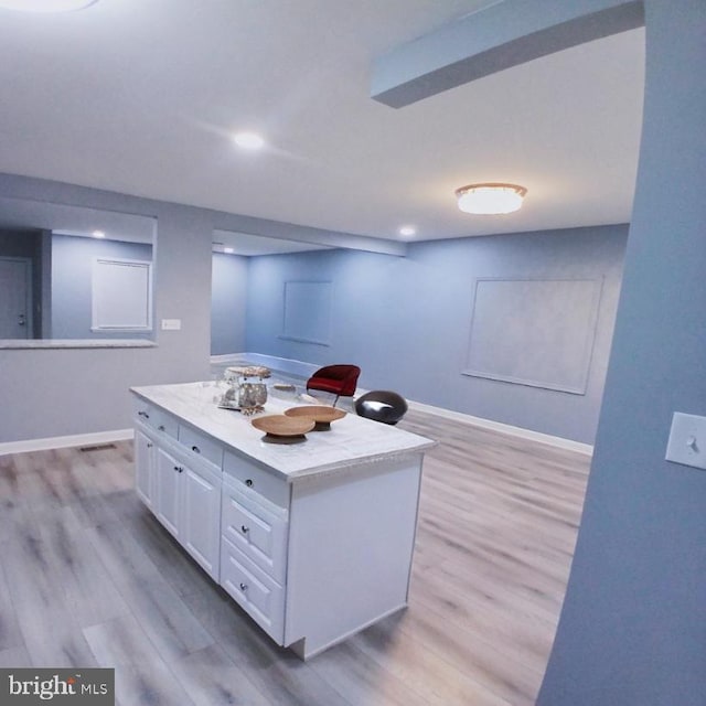 kitchen with baseboards, light countertops, light wood-style flooring, and white cabinets