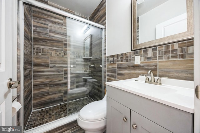 bathroom with tasteful backsplash, tile walls, vanity, toilet, and a shower with door