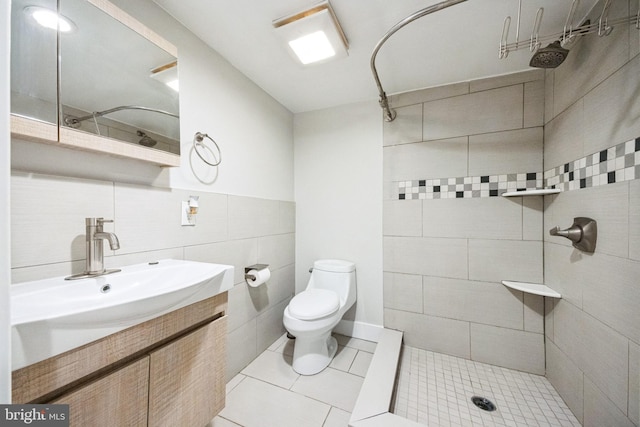 bathroom featuring vanity, tile walls, toilet, and tiled shower