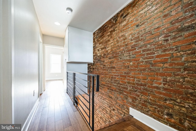 hallway featuring hardwood / wood-style flooring and brick wall