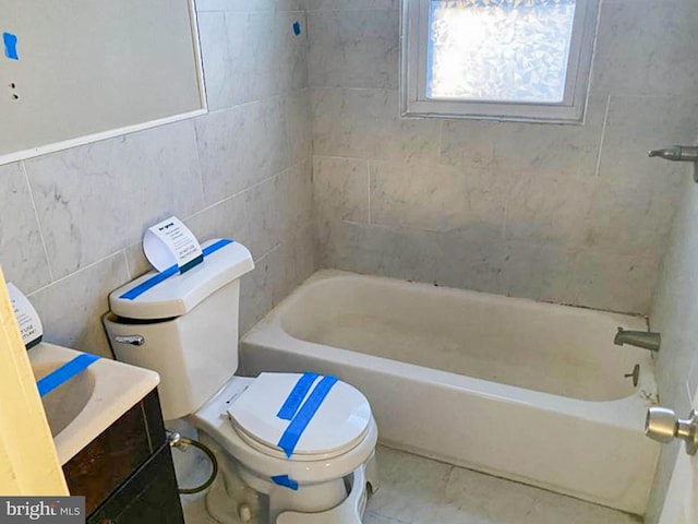 full bathroom with tile patterned floors, toilet, tile walls, vanity, and shower / washtub combination