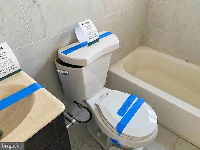 bathroom with tile walls, a bathtub, tile patterned floors, and toilet