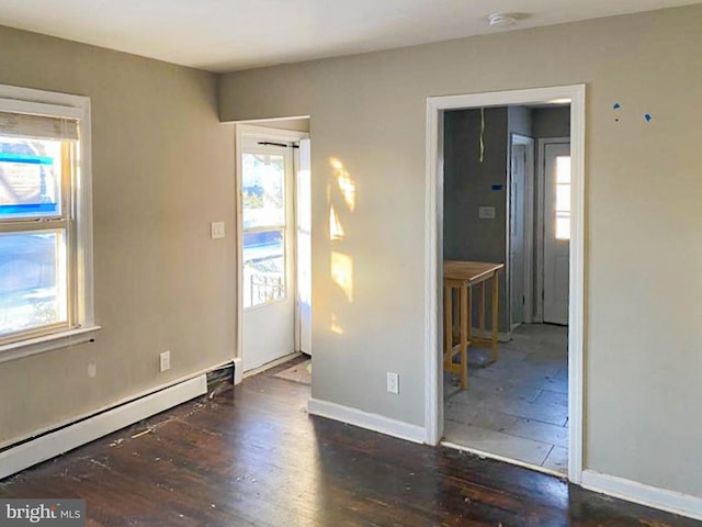 spare room with a baseboard heating unit and dark hardwood / wood-style floors