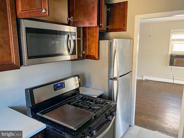 kitchen with light tile patterned flooring, a baseboard radiator, and appliances with stainless steel finishes