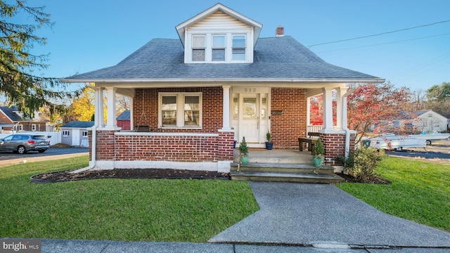 view of front of property with an outbuilding, a front yard, and covered porch