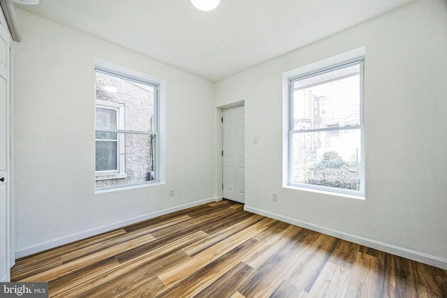 unfurnished bedroom featuring wood-type flooring and multiple windows