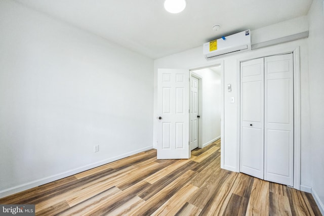 unfurnished bedroom featuring wood-type flooring, an AC wall unit, and a closet