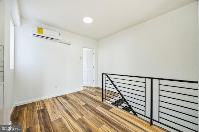 spare room featuring hardwood / wood-style floors and an AC wall unit