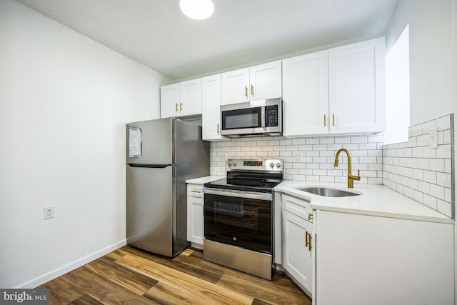 kitchen featuring appliances with stainless steel finishes, tasteful backsplash, white cabinetry, sink, and light wood-type flooring