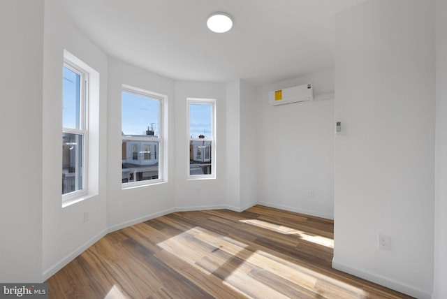 empty room with an AC wall unit and hardwood / wood-style floors