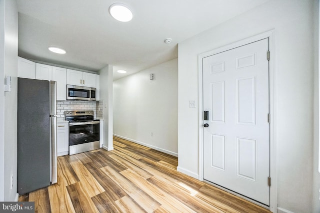 kitchen featuring white cabinetry, tasteful backsplash, stainless steel appliances, and light hardwood / wood-style floors