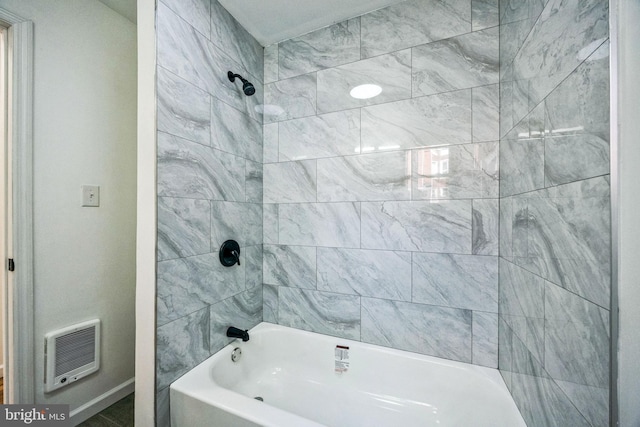 bathroom featuring heating unit and tiled shower / bath